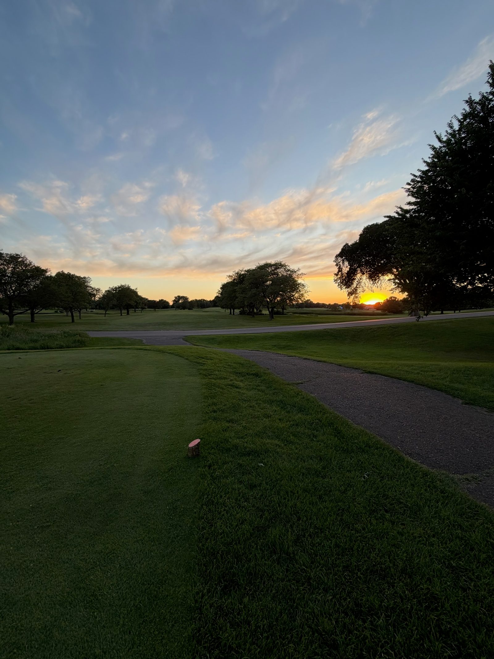 A tee box at sunset, the path ahead still lit